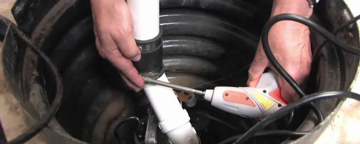 Sump pump installation technician connecting PVC discharge piping in Plymouth, MA